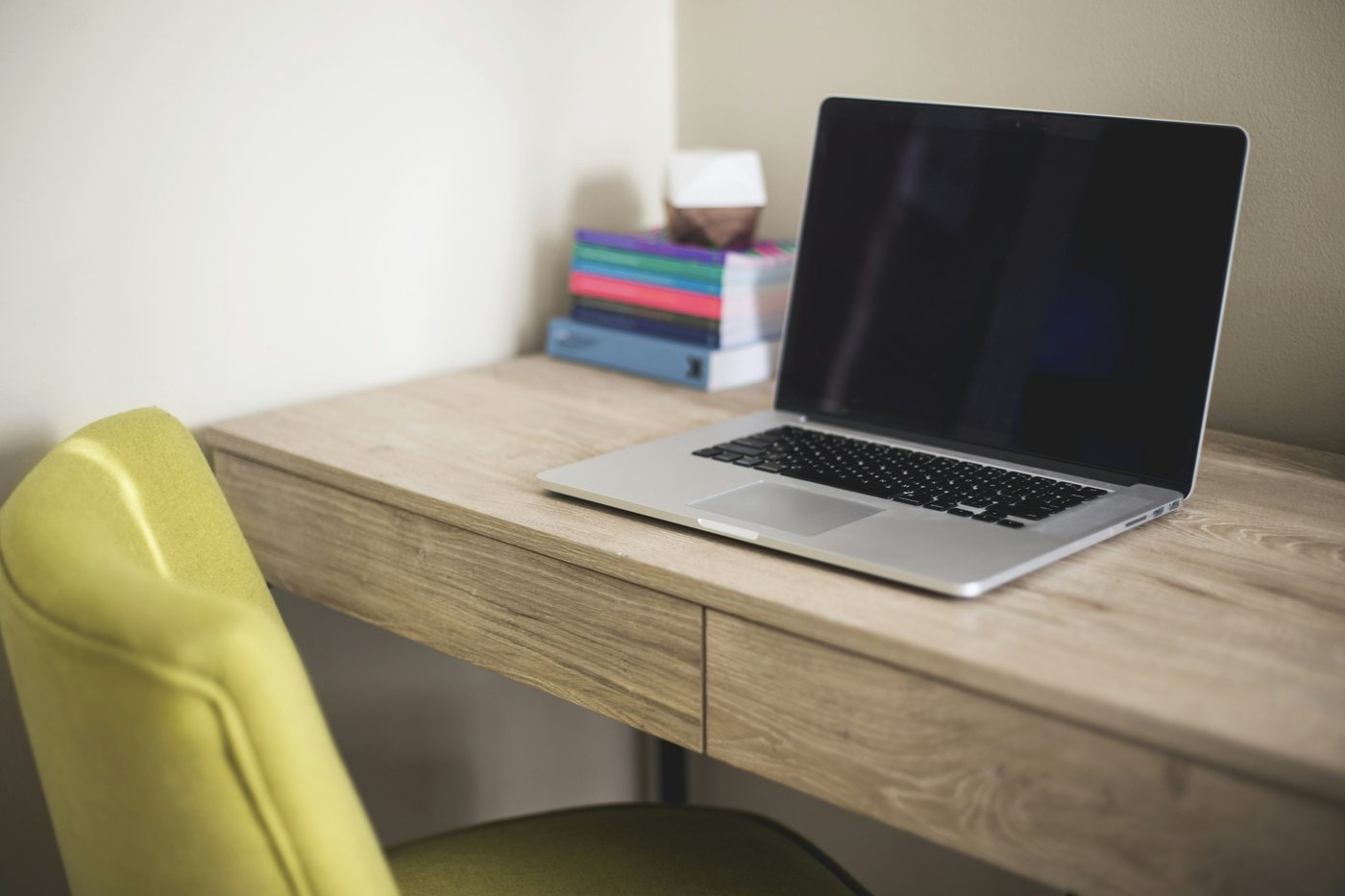 Open laptop on a light wooden desk beside books